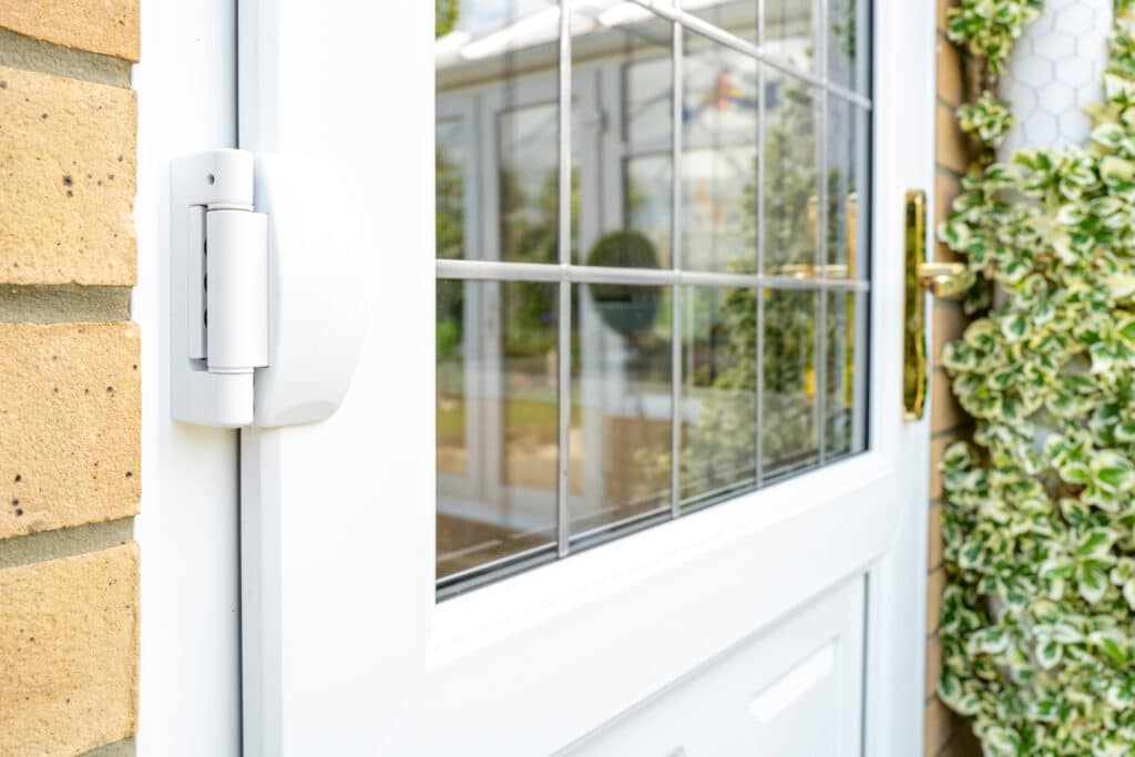 Shallow focus of door hinges seen on a newly installed double glazed PVC door which leads to a kitchen. Seen with installed leaded windows.